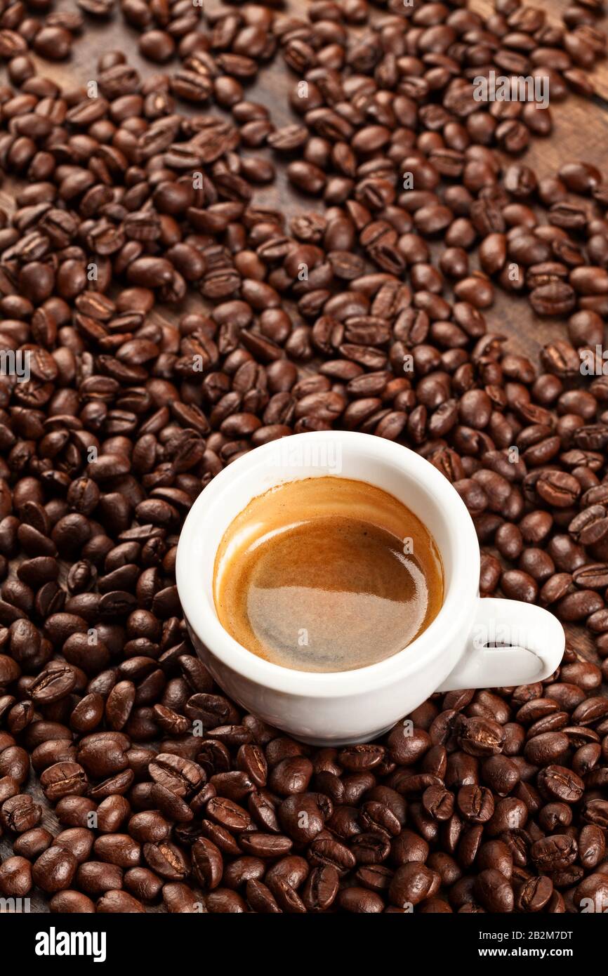 A cup of espresso with coffee beans scattered around